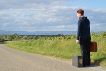woman on the road with old suitcases