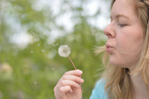 woman blowing a dandelion 