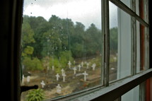 View of Grave markers in a small rural cemetery through a window. 