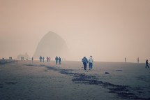 people walking on a foggy beach 