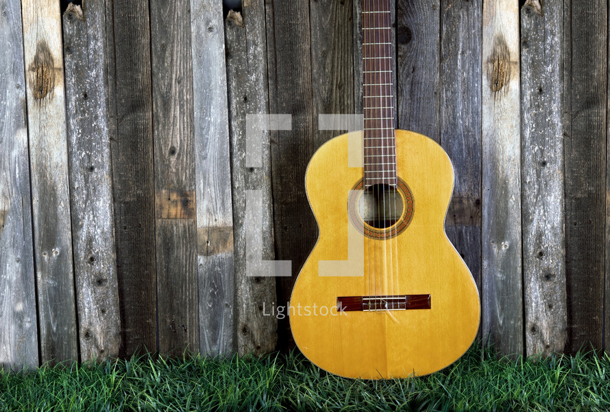 guitar leaning against a fence 