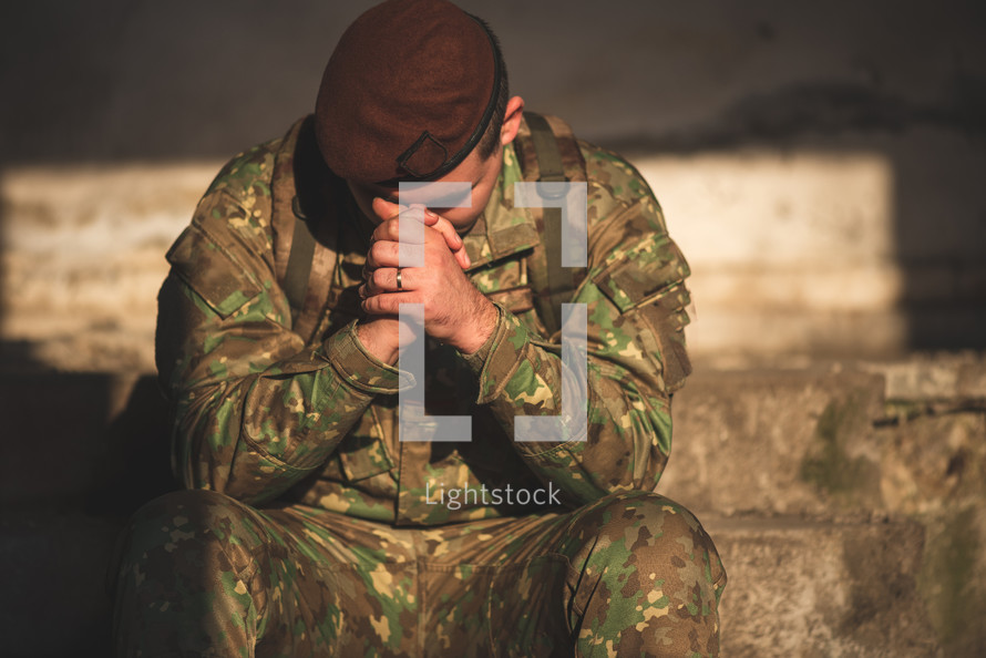 man in military uniform praying 