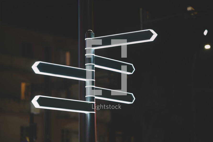 Modern-lit street directional arrows at night