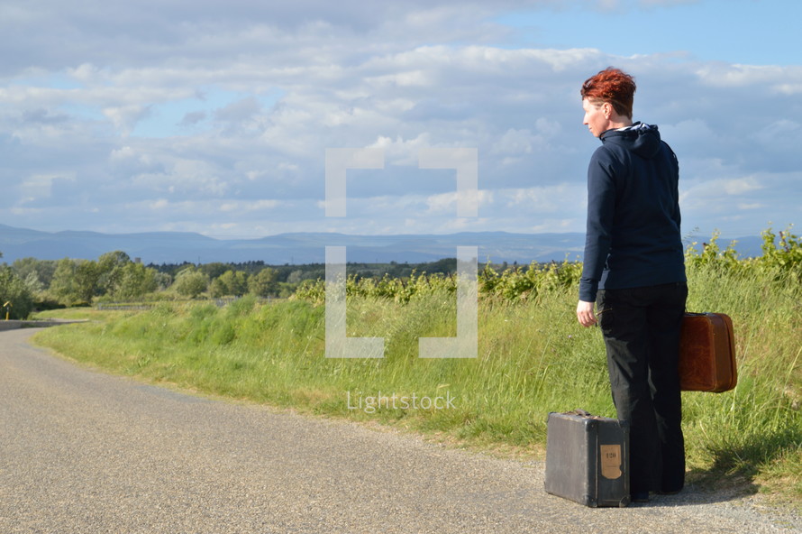 woman on the road with old suitcases