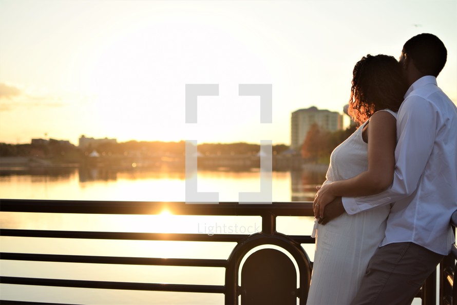 a couple embracing at sunset looking at water  