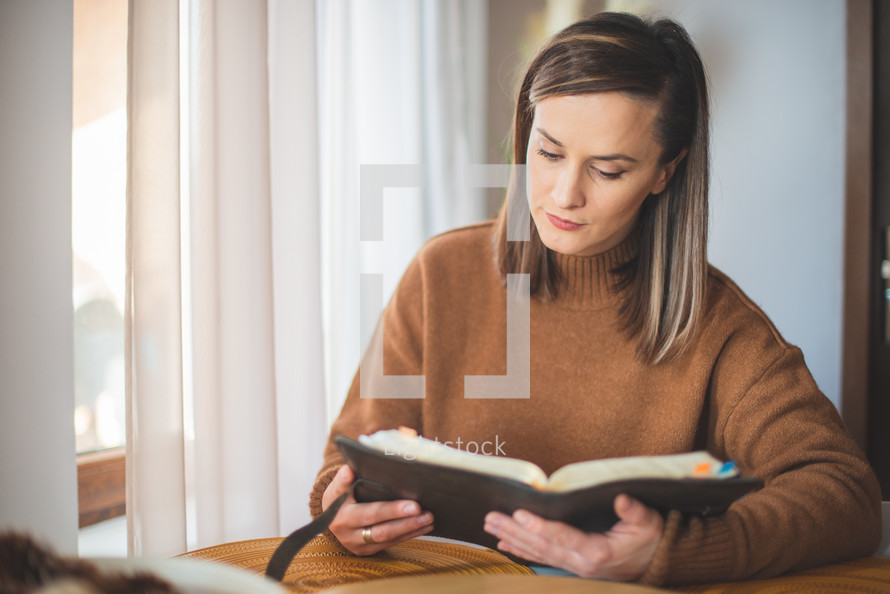 a woman sitting reading a Bible 