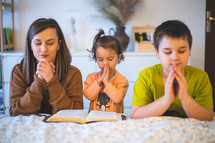 a mother praying with her children 