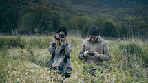 woman with a camera taking a picture in tall grass 