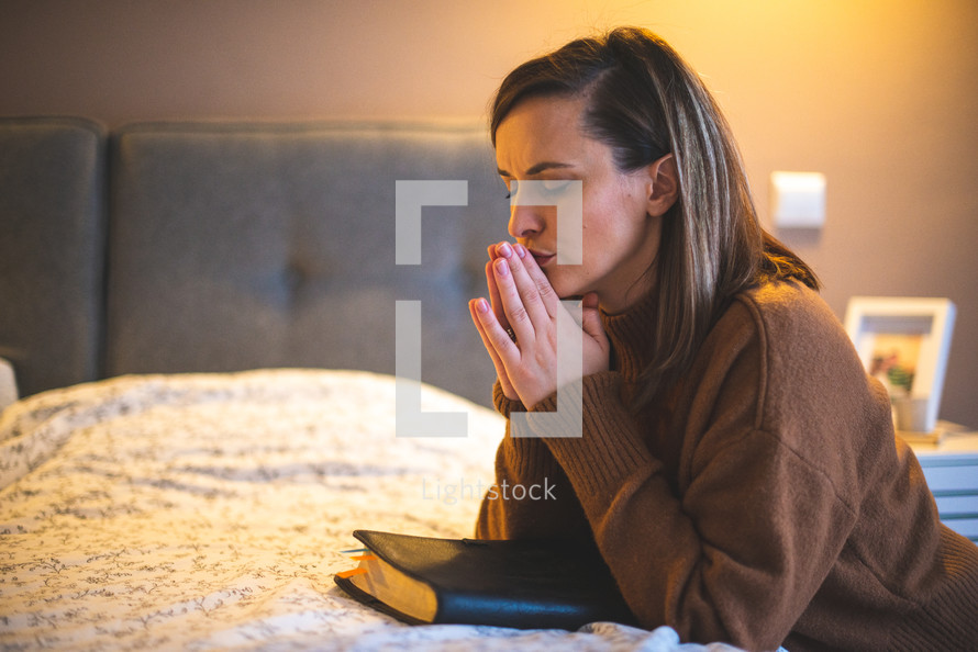 a woman kneeling at her bed praying 