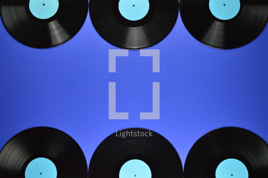 border of old black vinyl records with blank cyan labels on blue background
