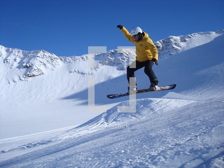 A man taking a jump on his snowboard.