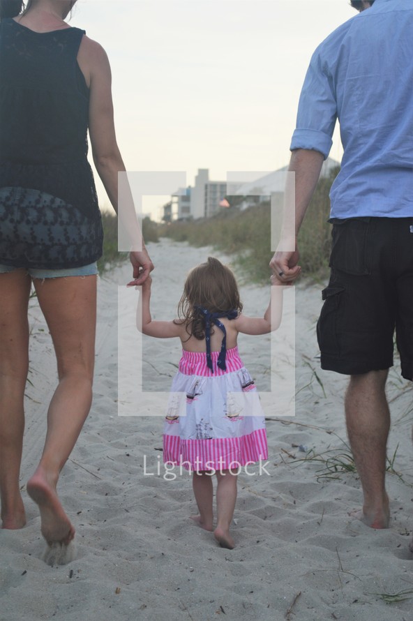 family walking holding hands on a beach 