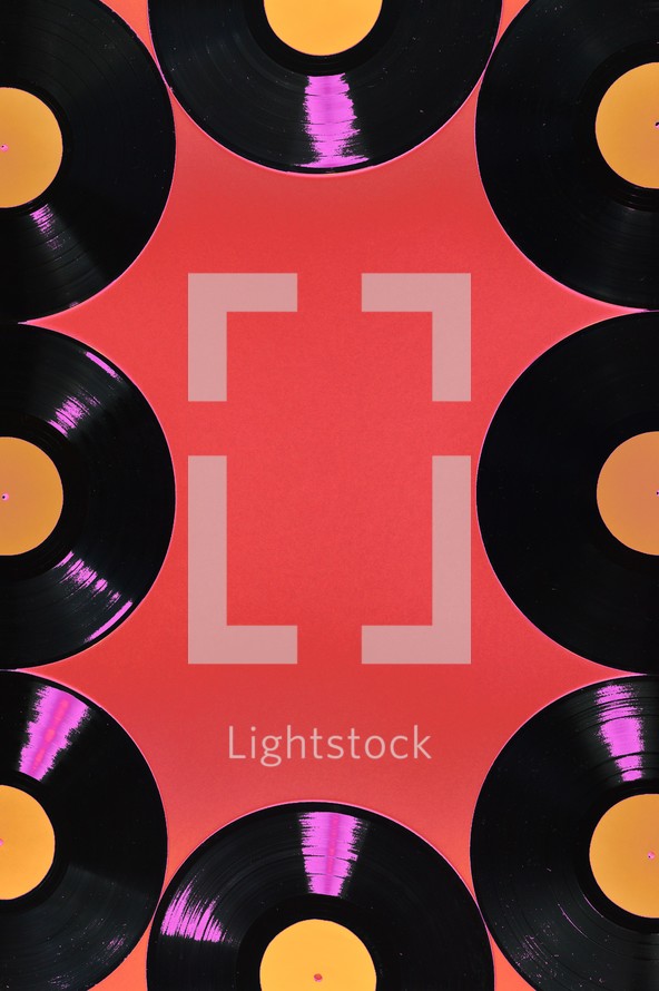 old black vinyl records with blank orange labels on red background as frame