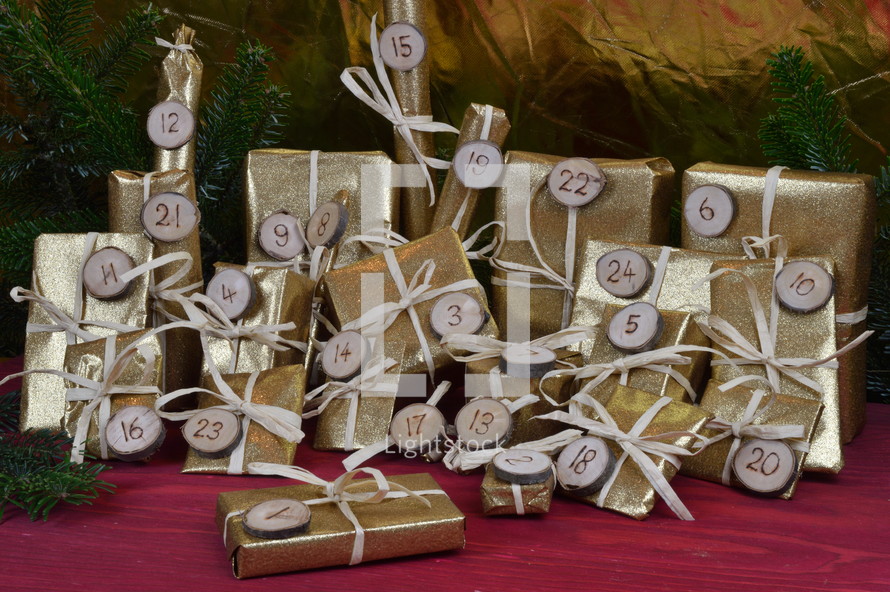 advent calendar with twenty four golden presents on red wood with the numbers burned into round wood pieces