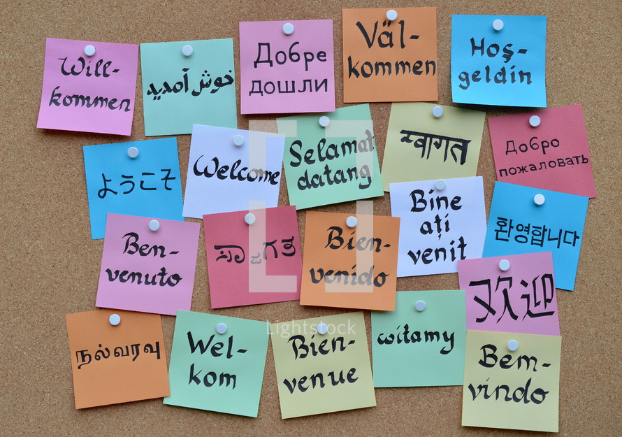 welcome in various languages on a cork board 