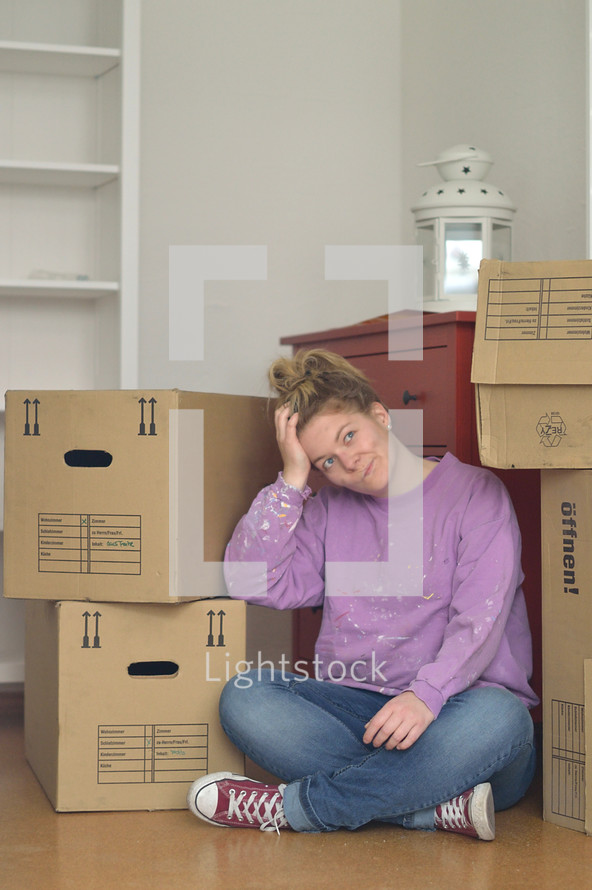 a woman sitting on the floor next to moving boxes 