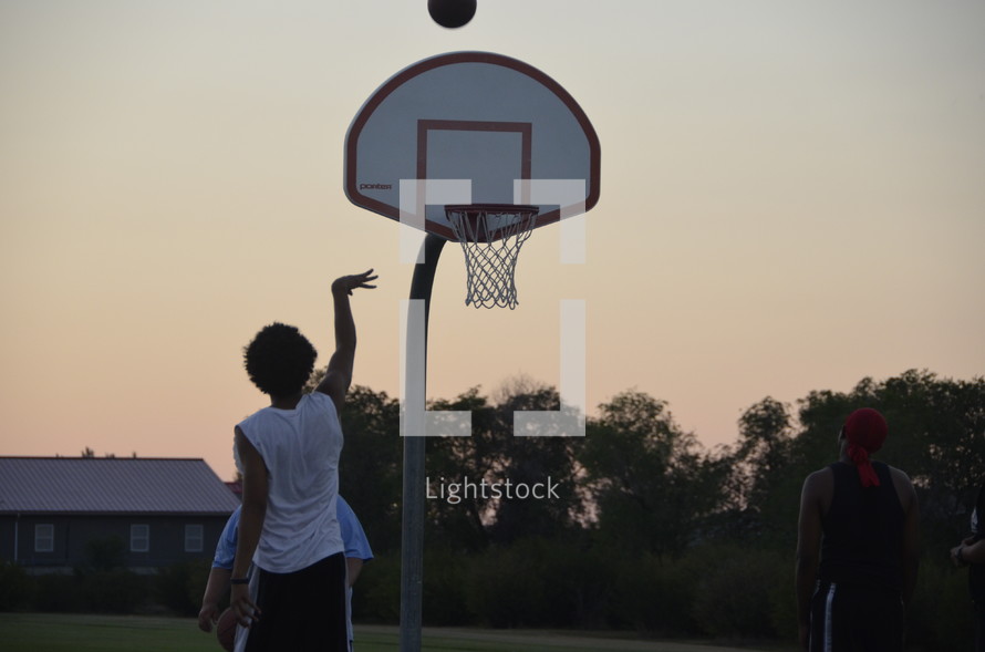 teens playing basketball at sunset 