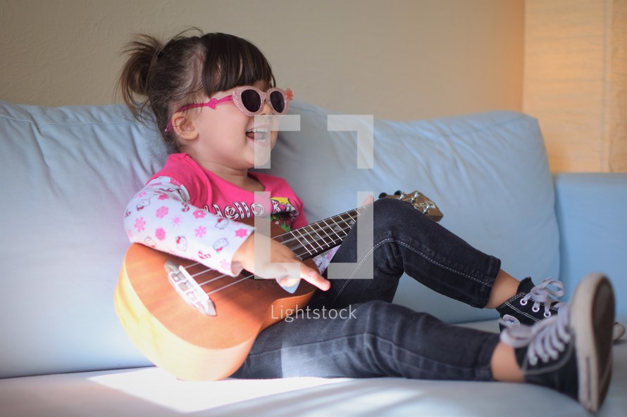 a giggle little girl playing a guitar in bed 