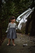 a little girl holding silver helium balloons 