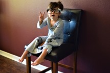 a little girl in glasses showing a peace sign 