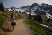a woman walking along a trail in the mountains