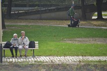 elderly couple sitting on a bench in a park