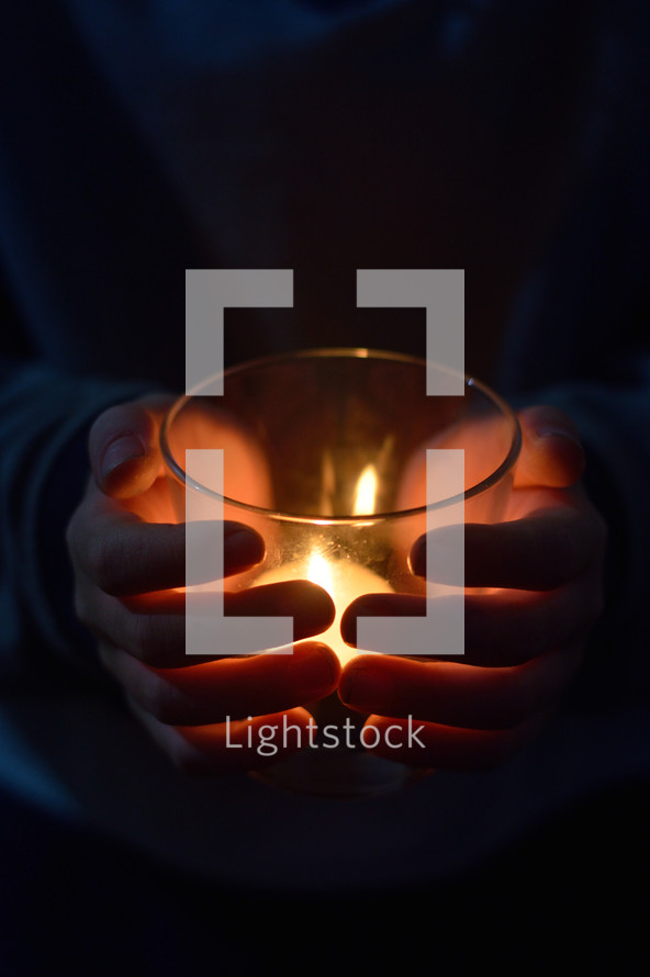 hands around a candle at a vigil 