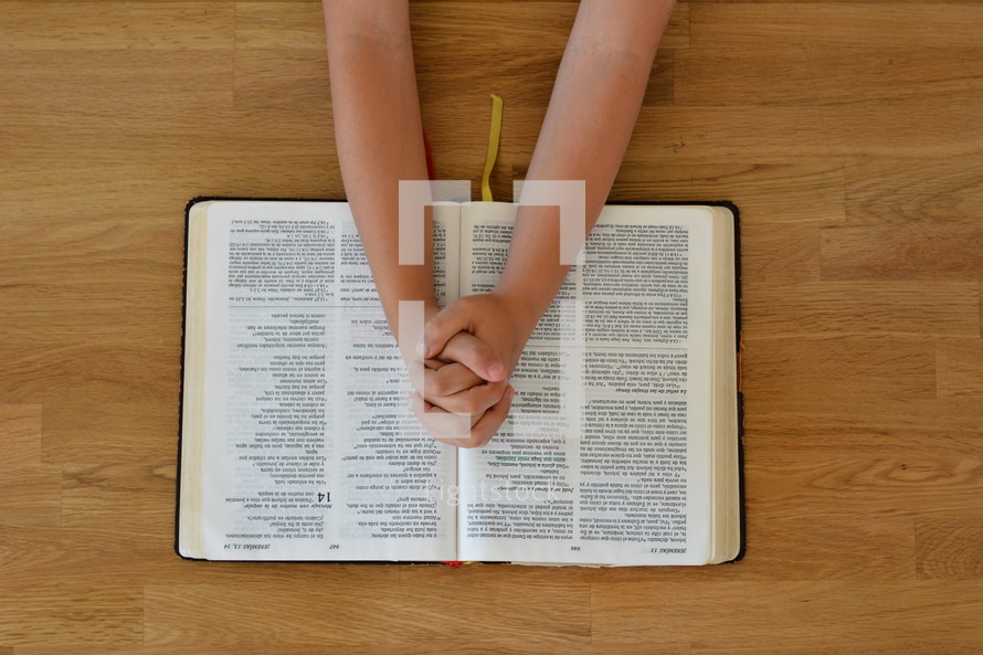praying hands over an open Bible 