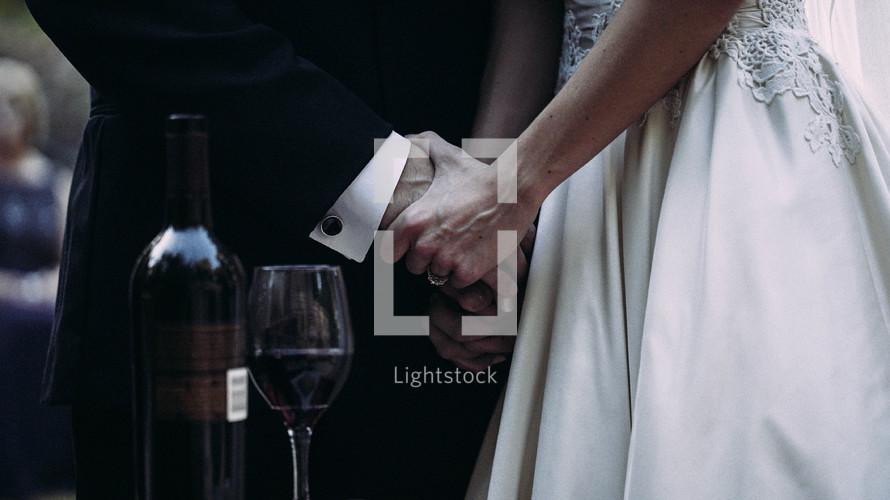 bride and groom holding hands and a wine bottle 