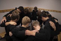 Young men in a huddle inside a locker room 