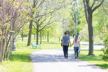 a couple walking holding hands in a park 