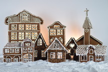 home made gingerbread village in front of white background on white snowlike velvet as advent decoration