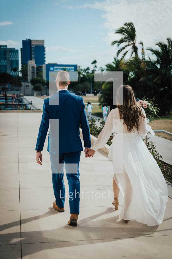 bride and groom walking on a city sidewalk 