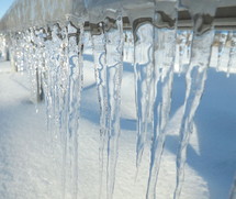 Icicles dripping toward to snowy ground. 