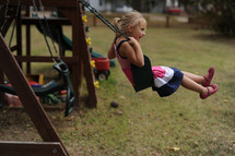 a little girl on a backyard swing set 