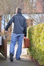 man leaving home with a suitcase for a journey