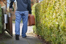 man leaving home with a suitcase for a journey