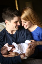 a mother and father holding a newborn infant 