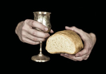 a man holding a chalice of wine and a loaf of bread 