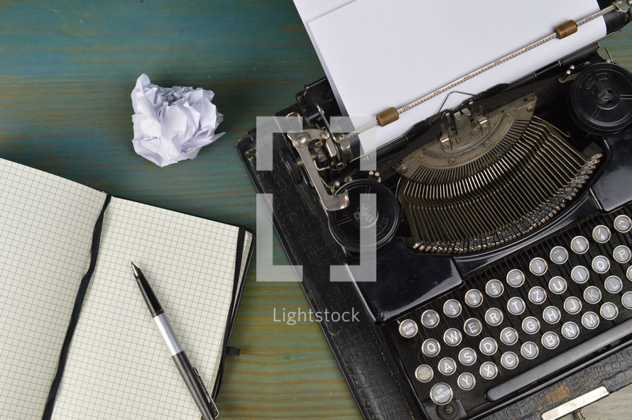 vintage typewriter with blank notebook, pen and crumbled ball of paper