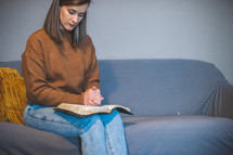 woman sitting on a couch praying 