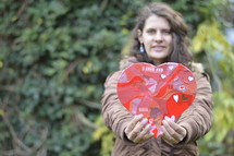 woman holding out a cutout paper heart