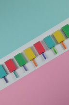 colorful row out of self made, crafted sponge popsicles between pink and light blue paper as thank you for the volunteer cleaning team in church or as decoration for the vacation bible school in the classroom