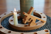 a candle and wood carving of Jesus bearing a cross 