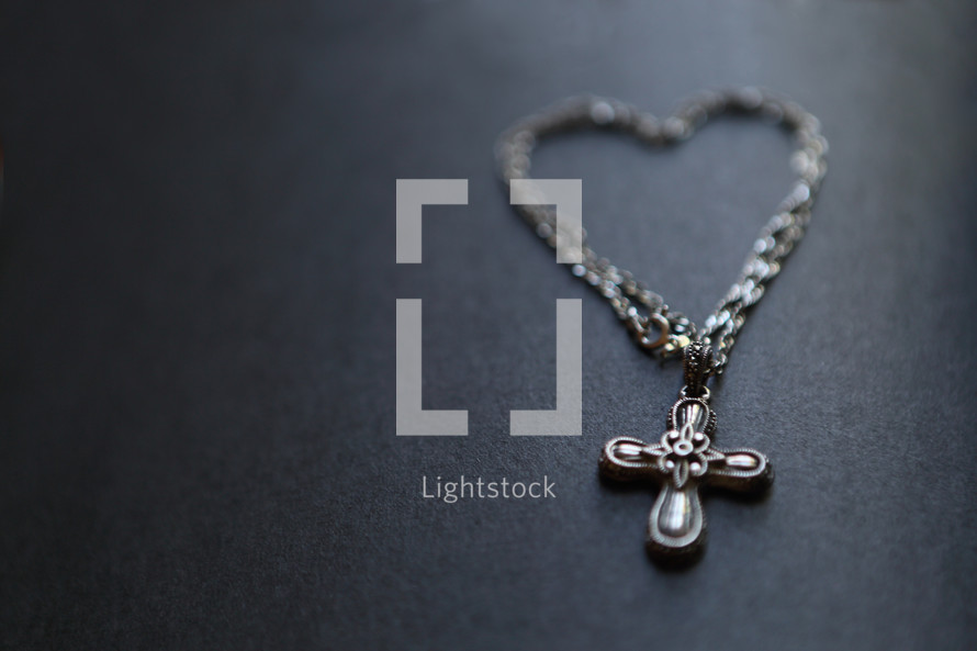 A metal bracelet shaped as a heart, with a cross pendant
