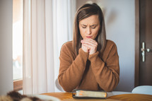 a woman sitting reading a Bible and praying 