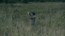 a man standing in a field taking a picture with a camera 