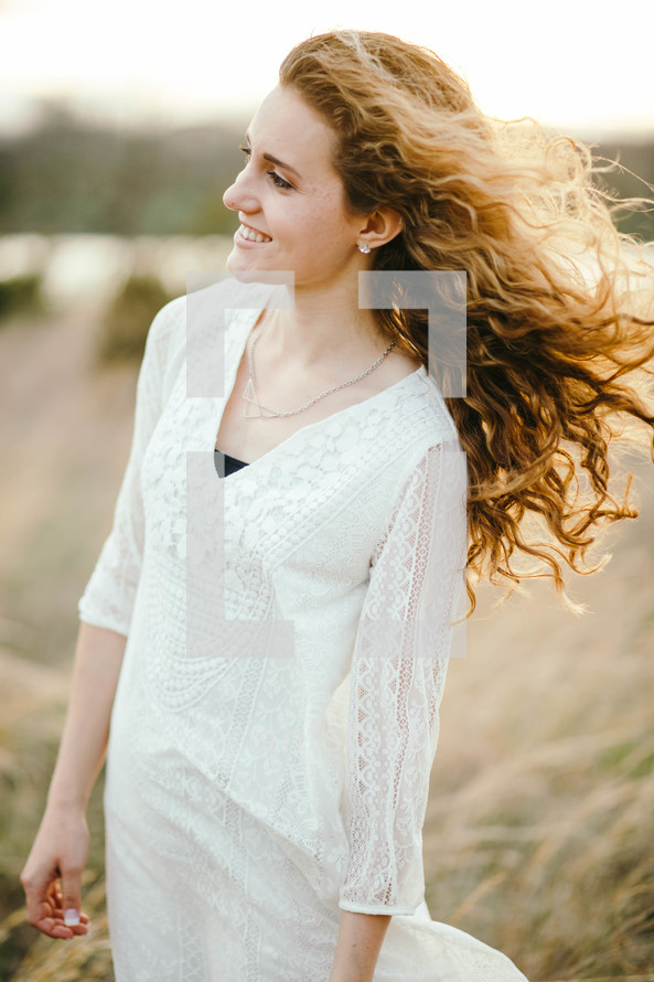 a woman with curly hair blowing in the breeze 