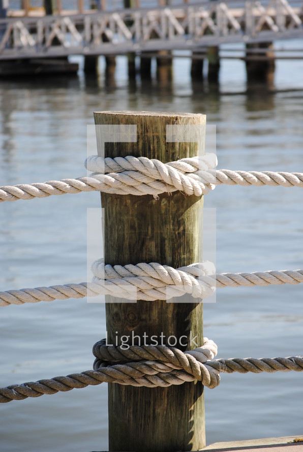 water pier post tied with 3 ropes