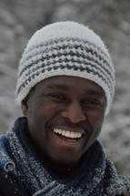 face of an African American man standing in the snow smiling 
